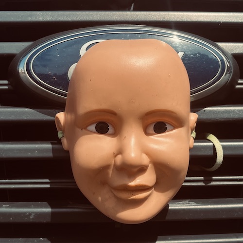 A plastic face mask strapped to the front of a van